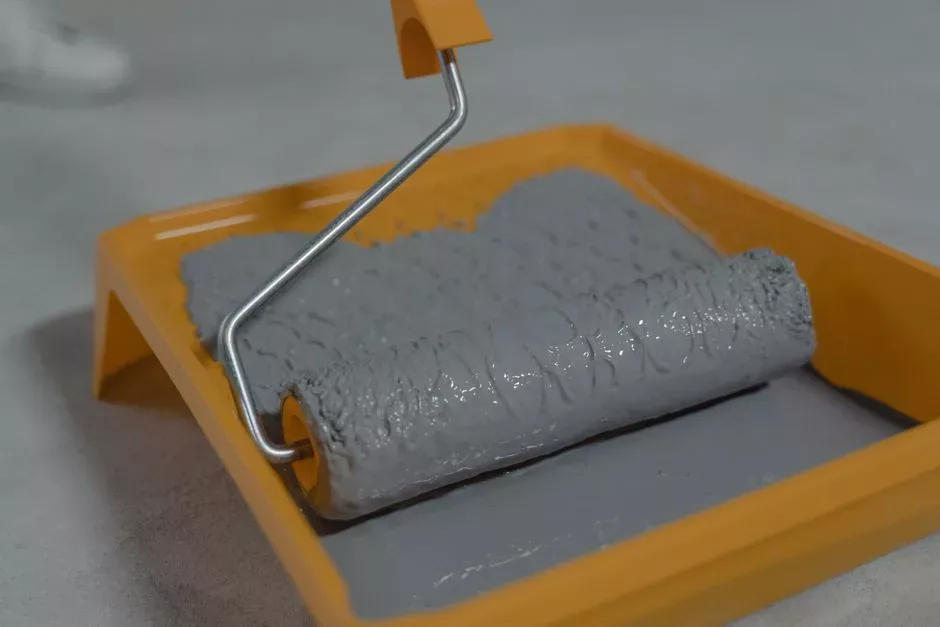 Rouleau appliquant une peinture grise, illustrant le choix d’une peinture résistante à l’humidité pour la rénovation d’une salle de bain.