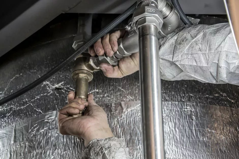 Plombier intervenant sous un lavabo pour démonter ou remplacer un siphon et réparer une évacuation d’eau.