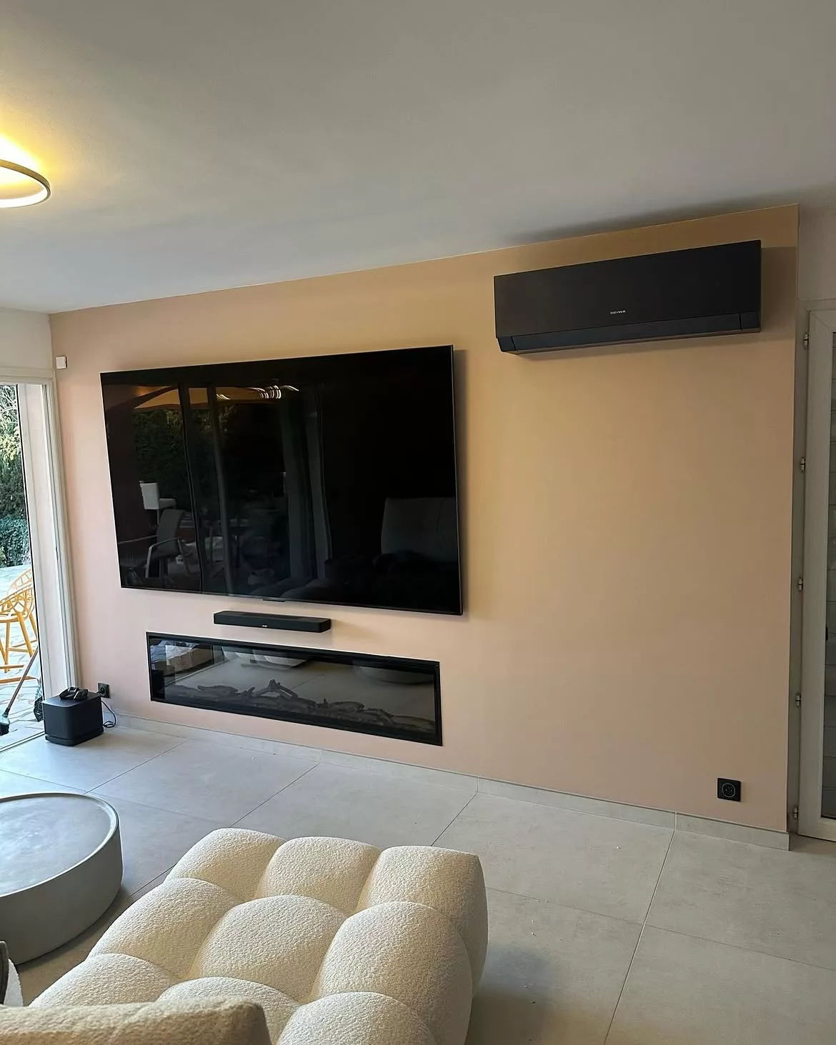 Mur d'agencement sur-mesure à Bandol avec télévision encastrée, cheminée électrique et climatisation mono-split Heiwa intégrée.