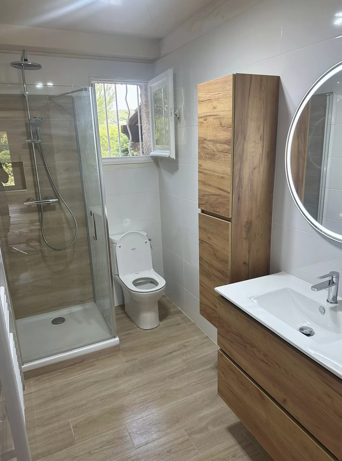 Vue d'ensemble de la salle de bain rénovée à Saint-Cyr-sur-Mer : douche à l'italienne, WC et meuble vasque en bois.