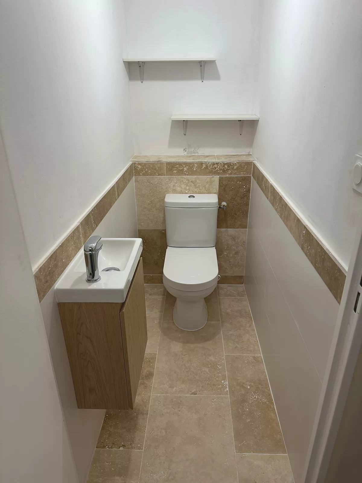 WC indépendants rénovés à Toulon avec frise en travertin et meuble vasque en bois.