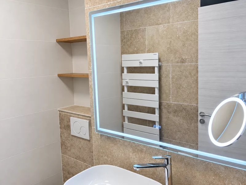 Vasque à poser blanche et meuble en bois clair, sous le miroir LED rétroéclairé.