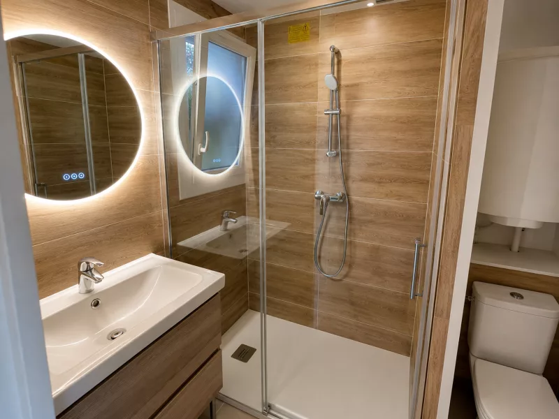 Vue d'ensemble de la salle de bain rénovée à Bandol, avec douche à l'italienne et vasques suspendues effet bois.