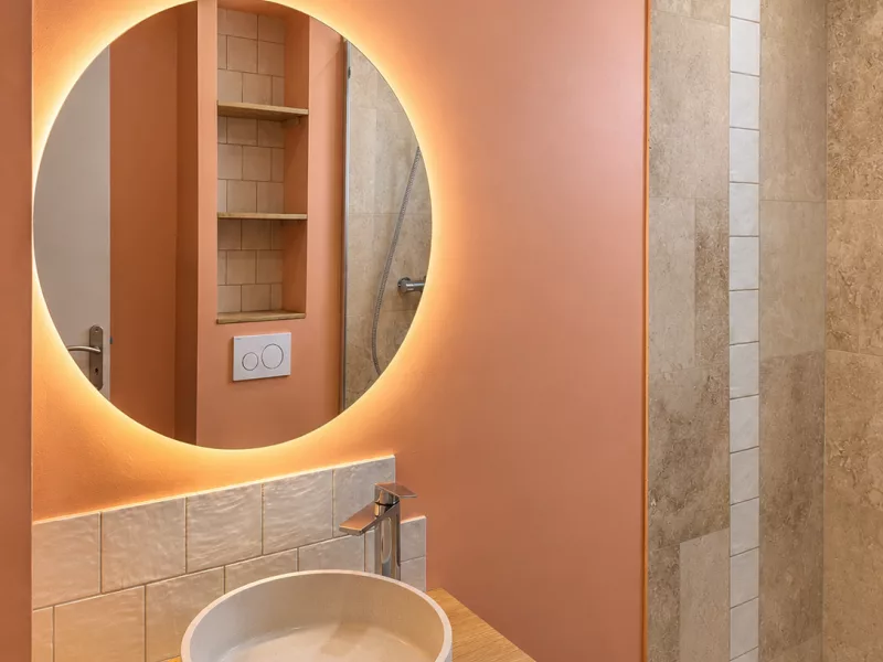 Meuble vasque en bois avec miroir rond rétroéclairé LED, salle de bain rénovée à Toulon.