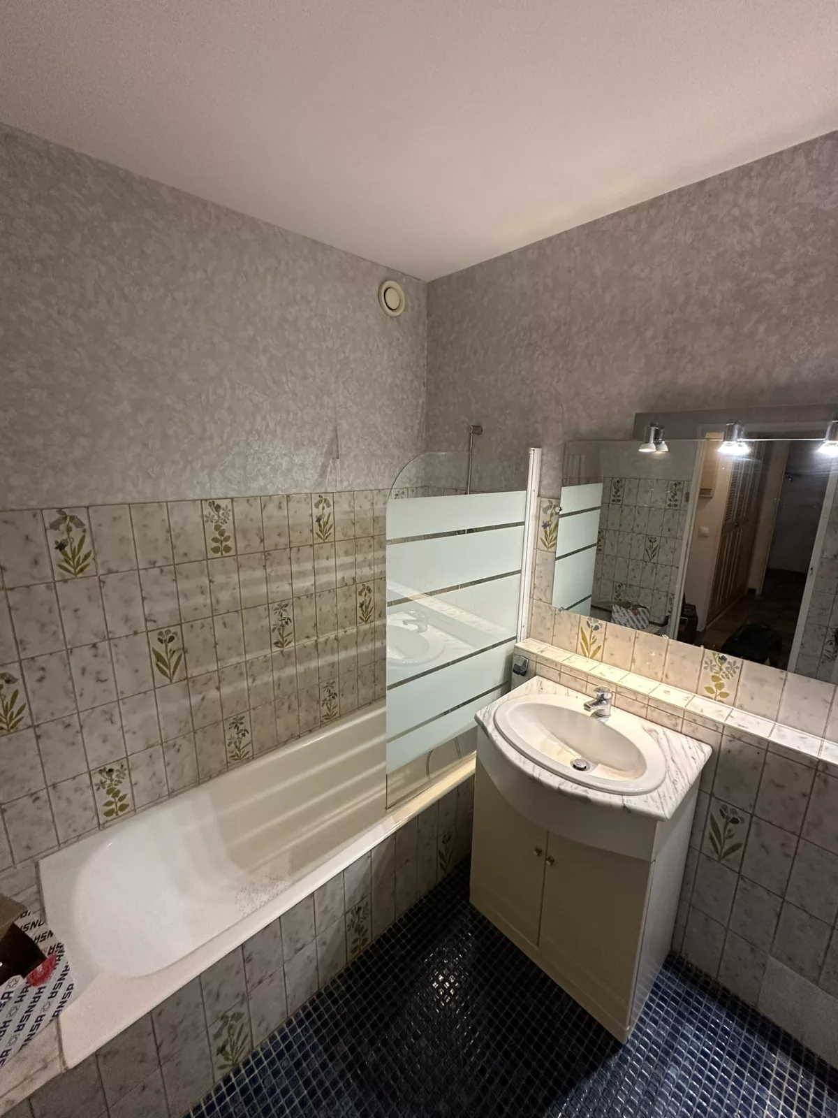 Ancienne salle de bain vétuste avant rénovation à Hyères : baignoire, faïence fleurie datée et meuble vasque à remplacer.