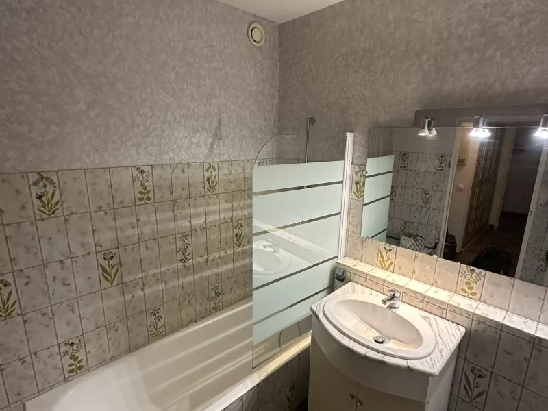 Ancienne salle de bain vétuste avant rénovation à Hyères : baignoire, faïence fleurie datée et meuble vasque à remplacer.
