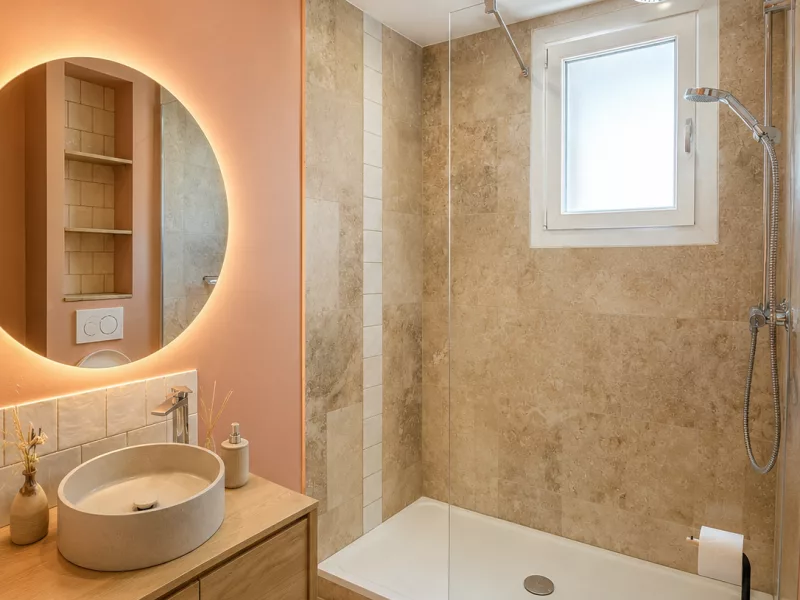 Vue d'ensemble de la salle de bain rénovée à Toulon : douche à l'italienne, vasque et WC suspendu.