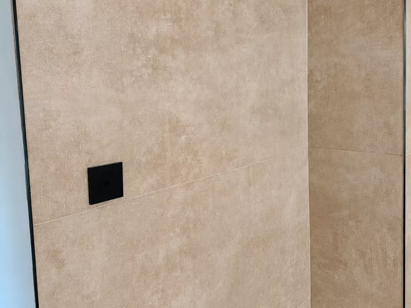 Détail du carrelage grand format effet béton et appareillages noir, rénovation salle de bain à Aix-en-Provence.
