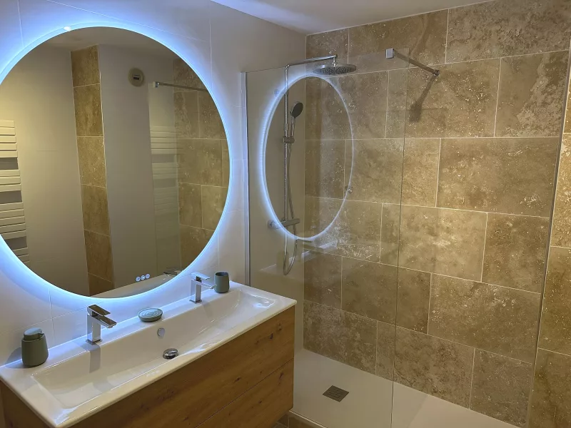 Colonne de douche avec pluie de douche et douchette sur mur en travertin véritable, salle de bain à Toulon.