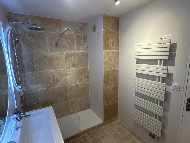 Douche à l'italienne avec colonne de douche et travertin, rénovation de salle de bain à Toulon.