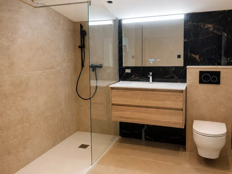 Vue d'ensemble de la salle de bain rénovée à Aix-en-Provence : douche à l'italienne, meuble vasque et WC suspendu.